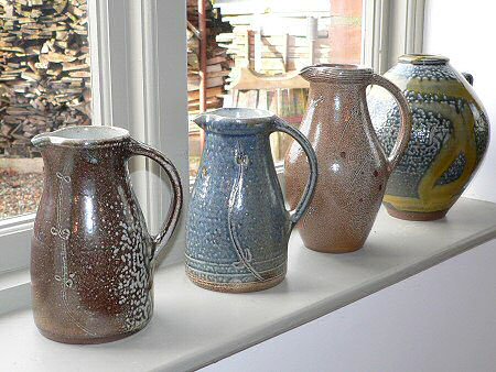 Salt glazed jugs and vase with wood store behind