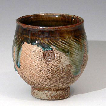 Spirally decorated stoneware tea bowl with dripped glaze.
